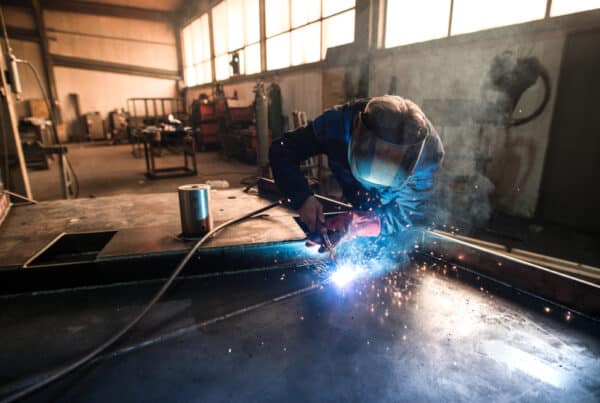 A welder performing MIG welding in an industrial workshop