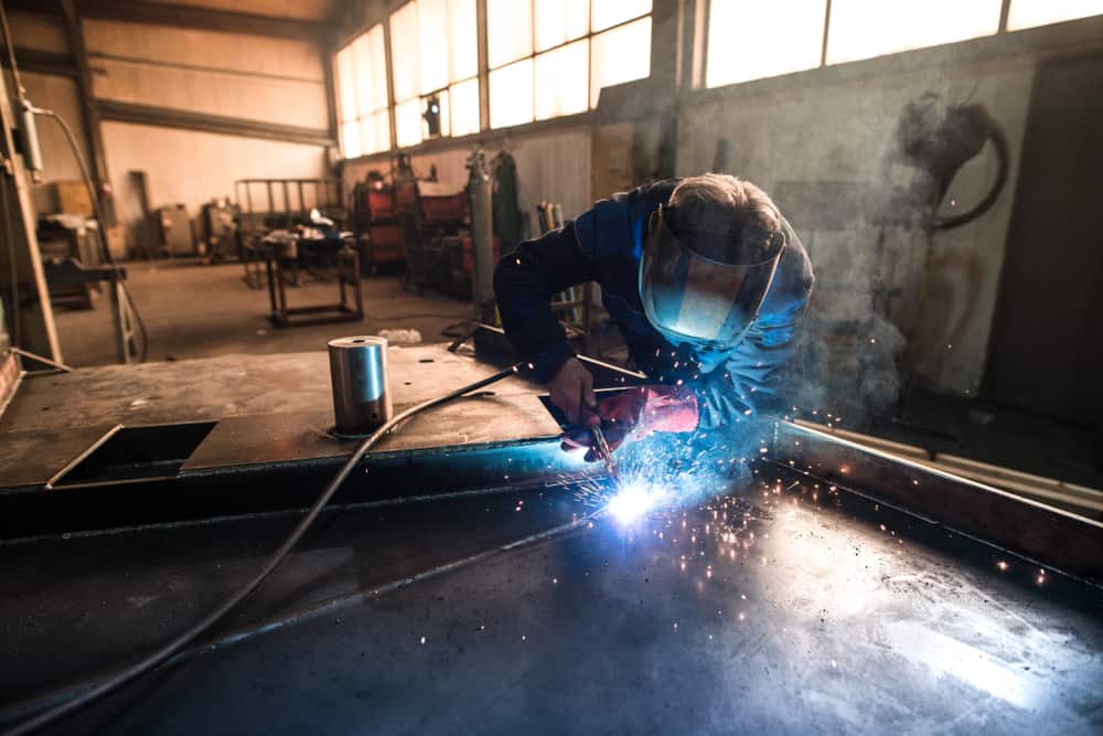 A welder performing MIG welding in an industrial workshop