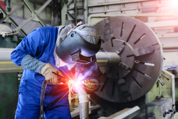 A Welder using a welding positioner to hold a workpiece